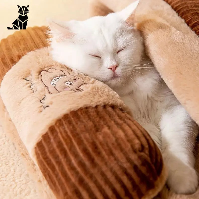 Chat blanc confortablement endormi sur une couverture marron dans le Cozy Winter Cat Bed, parfait pour le couchage